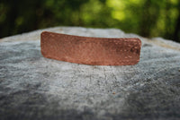 Copper hammered metal object on wood